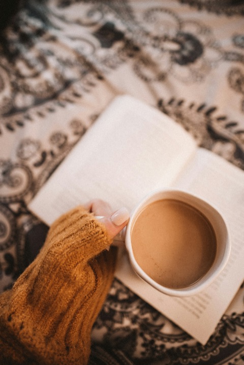 Main tenant un café crème au-dessus d'un carnet ouvert