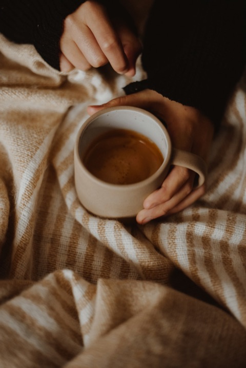 Mains autour d'un café serré dans un plaid rayé aux tons chauds