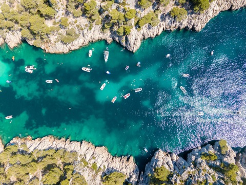Vue aérienne d'une calanque aux eaux turquoise près de Marseille, quelques bateaux au mouillage