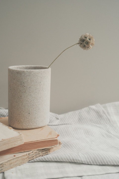 Vase en céramique artisanale posé près d'un lin froissé, lumière douce