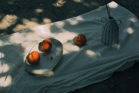 Oranges sur un plateau, nappe blanche mouchetée de lumière